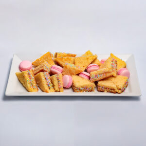 The Sweet selection Platter featuring slices of golden corn cake and pink macarons decorated with colourful sprinkles