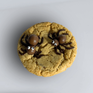 Creepy Crawly Cookie Halloween cookie featuring crumbly golden base with chocolate spiders and cartoon-style white eyes