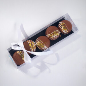 Dubai Chocolate Macaron set featuring dark chocolate macarons with light drizzle gold toppings, neatly arranged in a gift box tied with a white ribbon