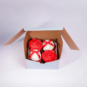 Ribbons and Roses cupcakes set of four in a brown cardboard box, each topped with red rose-shaped frosting and decorated with a red ribbon bow.