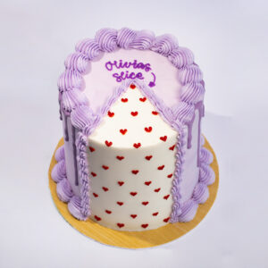 Slice Slice cake with lavender piped frosting, white top surface with red heart sprinkles, and “Olivia’s slice” text on top.