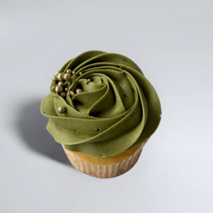Matcha cupcake with light golden sponge base and vibrant green matcha frosting piped in a rose-style swirl design.