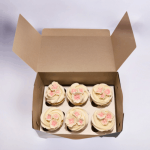 Box of 6 Petal & Pearls Cupcakes with cream frosting and pink floral decorations arranged in an open gift box.