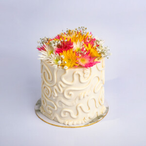 Mini Mom's Flower Pot Cake with textured white frosting and a vibrant floral topper featuring yellow, pink, and white flowers