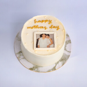 Mini Mom's Flower Pot Cake with white frosting, yellow message icing, and a framed mother-and-child photo displayed on top of the cake