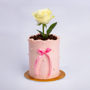 Mini Mom's Flower Pot Cake with pink ] frosting, pearl accents, ribbon detail, and yellow rose toppers.
