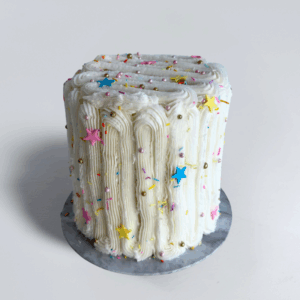 White textured Confetti Party cake with colourful star and rainbow sprinkles, gold sugar pearls and a grey marble cake board.