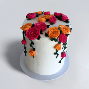 Rose Garden floral cake with fuchsia and orange buttercream roses and green leaves